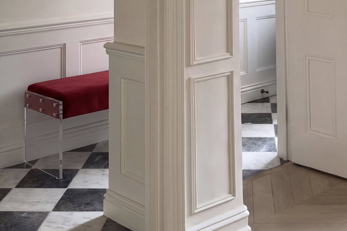 Interior hallway with an open door, a red bench, and patterned flooring featuring black and white tiles.