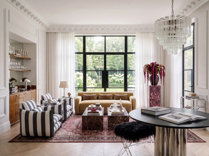 Living room with striped chairs, a yellow sofa, two coffee tables, large windows, and a tall chandelier.